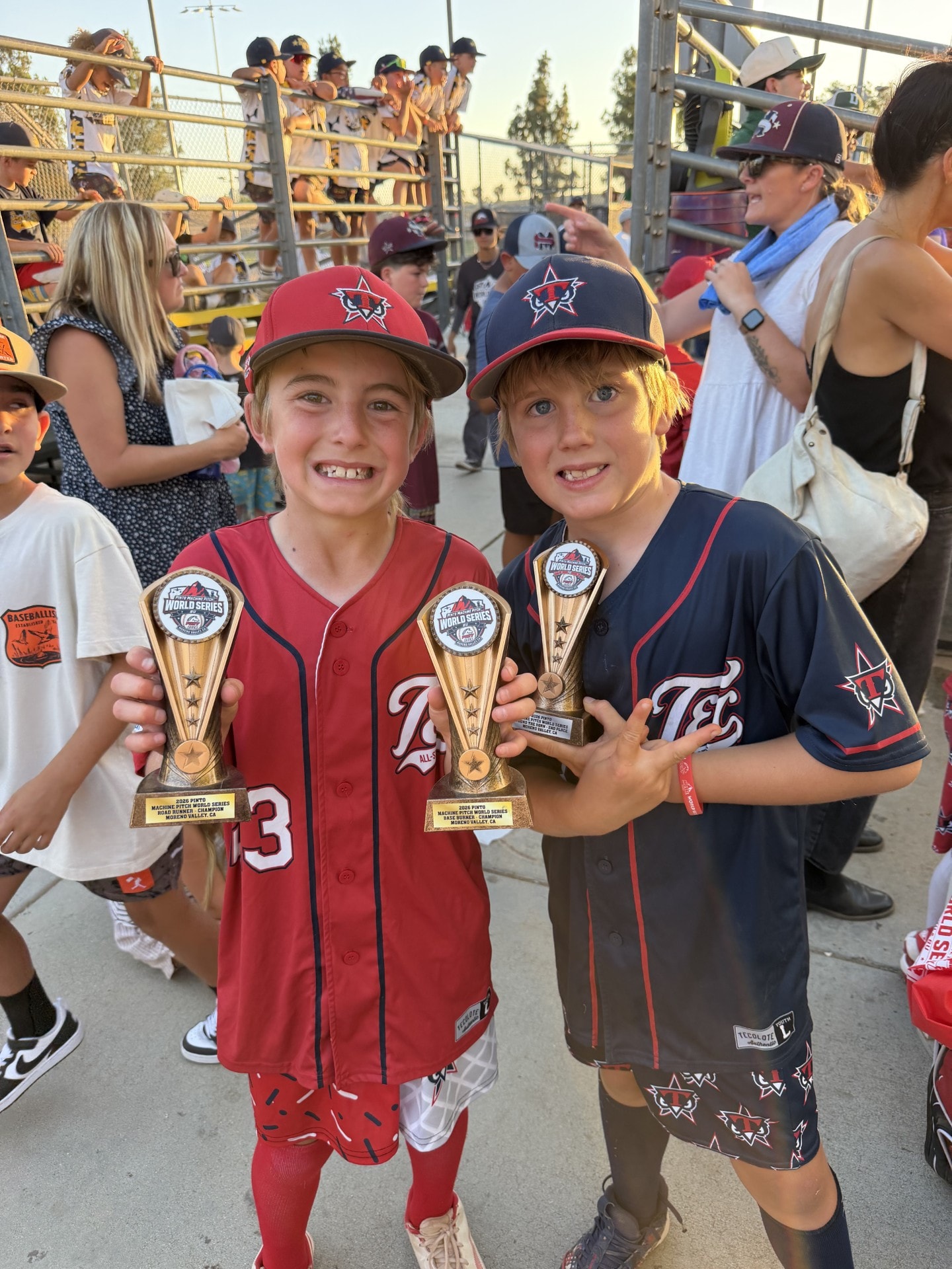 Two children holding baseball championship trophies